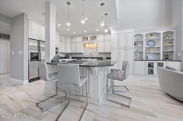 kitchen with a breakfast bar area, white cabinets, visible vents, and stainless steel fridge