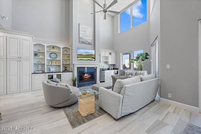 living room featuring plenty of natural light, a ceiling fan, baseboards, and a high end fireplace