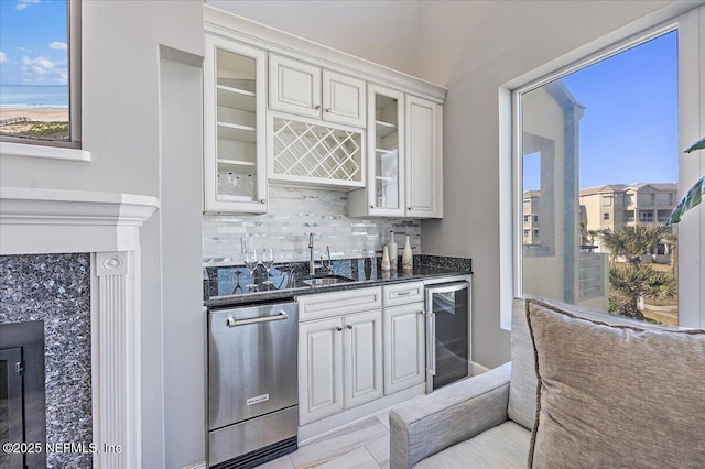 kitchen featuring a sink, wine cooler, glass insert cabinets, dishwasher, and tasteful backsplash