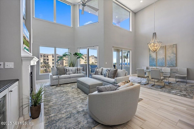 living area with baseboards, light wood-style flooring, and ceiling fan with notable chandelier