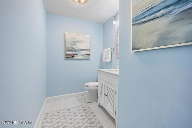 bathroom featuring vanity, baseboards, a textured ceiling, tile patterned floors, and toilet