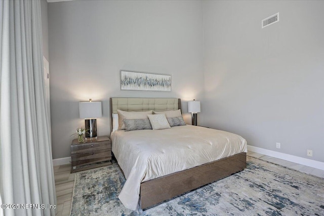 bedroom with wood finished floors, baseboards, and visible vents