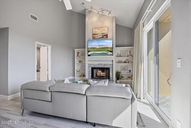 living room featuring visible vents, high vaulted ceiling, a ceiling fan, a premium fireplace, and baseboards