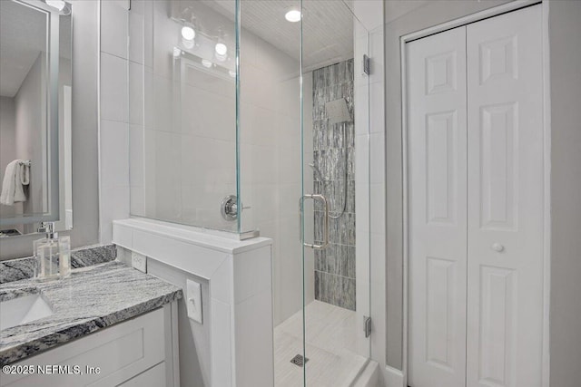 full bath with vanity, a stall shower, and a closet