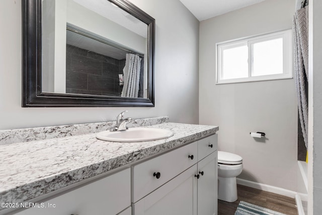 full bathroom featuring baseboards, toilet, wood finished floors, and vanity