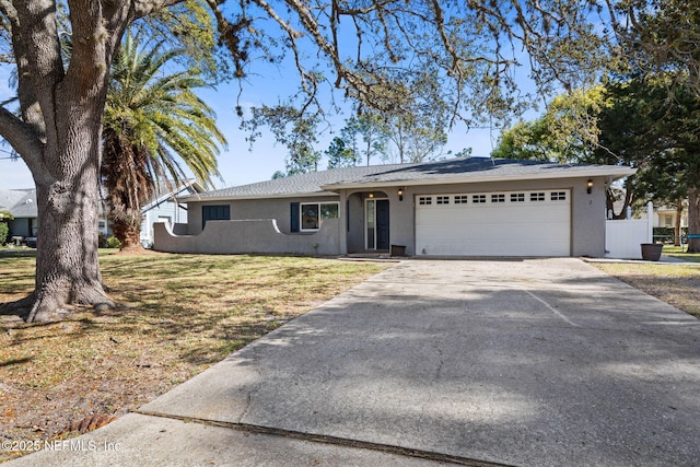 ranch-style home with stucco siding, concrete driveway, a garage, and a front yard