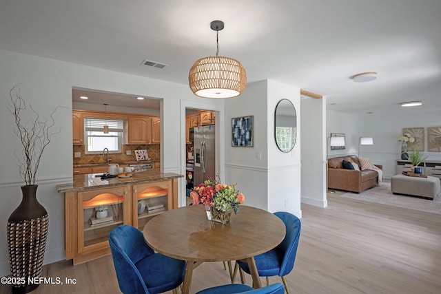 dining space featuring light wood-type flooring and visible vents