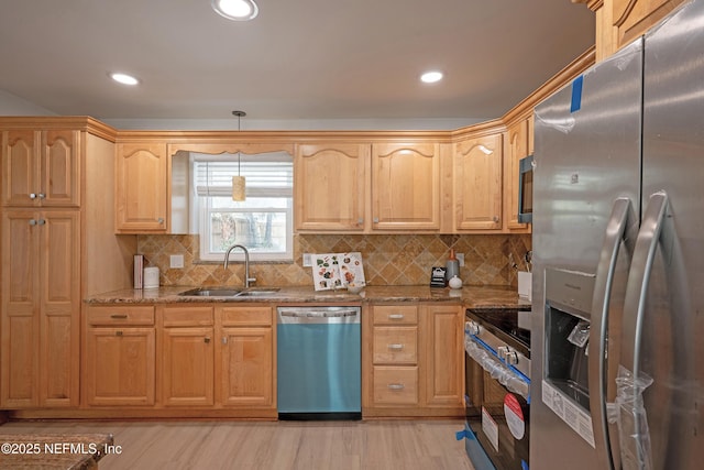 kitchen with light stone counters, a sink, stainless steel appliances, pendant lighting, and tasteful backsplash