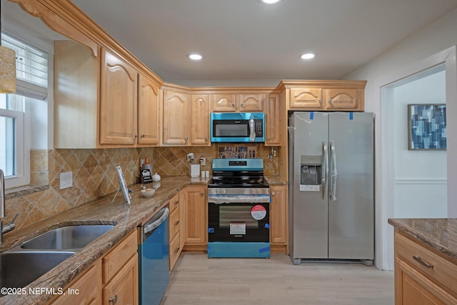 kitchen with dark stone countertops, light wood-style flooring, tasteful backsplash, and stainless steel appliances