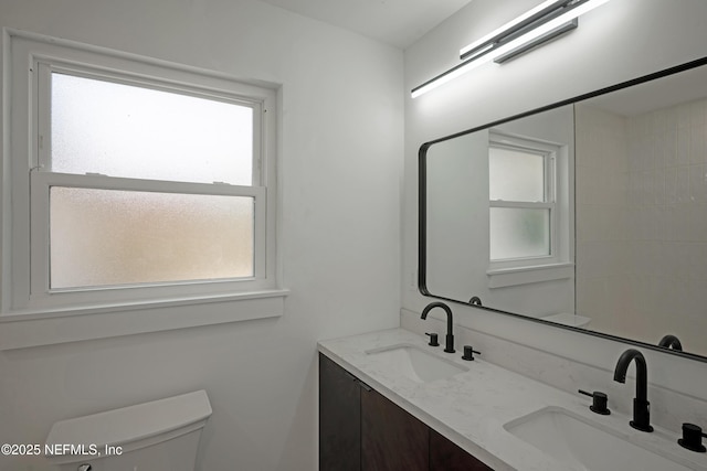 bathroom with double vanity, toilet, and a sink