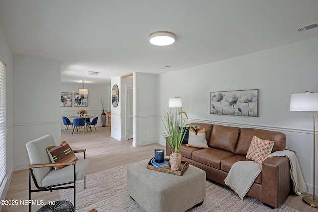 living room with visible vents, baseboards, and light wood-style flooring