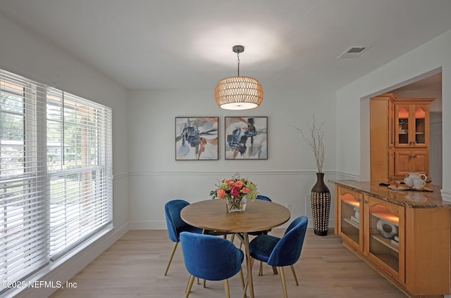 dining space featuring light wood-type flooring, visible vents, and baseboards