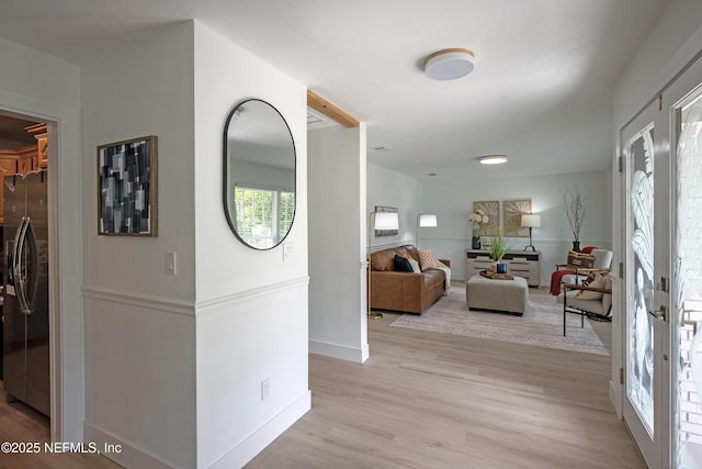 hallway with french doors, light wood-type flooring, and baseboards