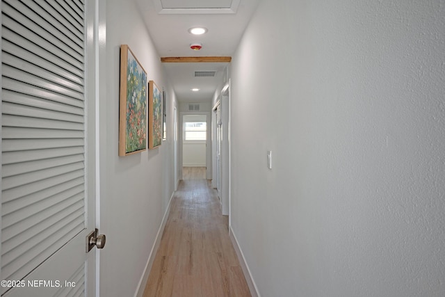 hallway with visible vents, light wood-type flooring, and baseboards