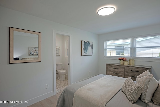 bedroom with ensuite bath, baseboards, and wood finished floors