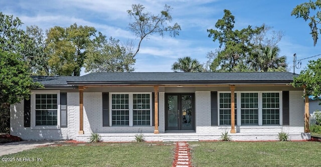 ranch-style home with a front lawn, a porch, french doors, roof with shingles, and brick siding