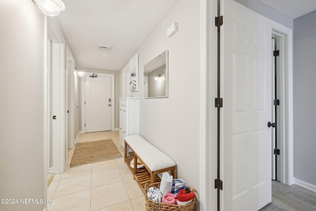 hall featuring light tile patterned floors, visible vents, and baseboards