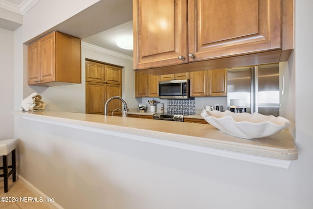 kitchen featuring a peninsula, a sink, ornamental molding, light countertops, and stainless steel appliances