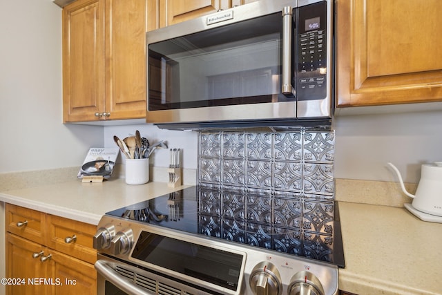 kitchen with stainless steel appliances, brown cabinetry, and light countertops