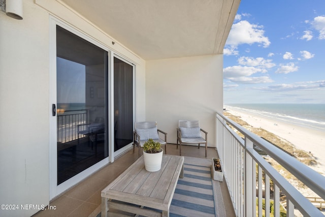 balcony featuring a view of the beach and a water view