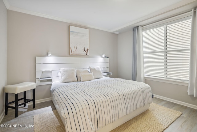 bedroom with wood finished floors, baseboards, and ornamental molding