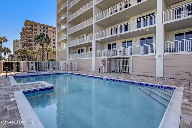 pool featuring a community hot tub and fence