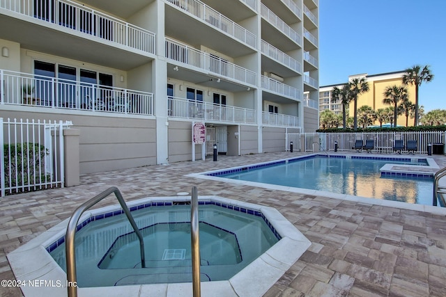 pool featuring a community hot tub, a patio, and fence