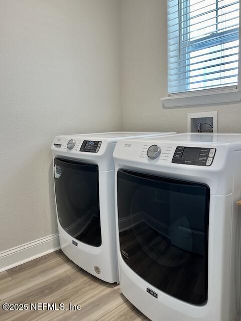 clothes washing area featuring laundry area, light wood-style flooring, separate washer and dryer, and baseboards