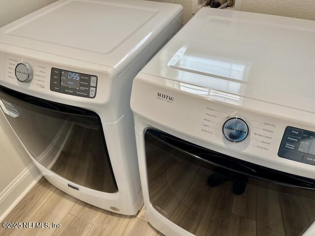 washroom featuring laundry area, light wood-style flooring, and washing machine and clothes dryer