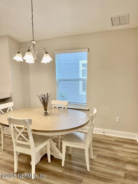 dining space featuring a notable chandelier, visible vents, baseboards, and light wood-style floors