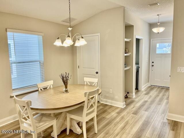 dining space featuring light wood-type flooring, baseboards, visible vents, and a chandelier