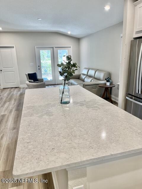 kitchen with vaulted ceiling, light wood finished floors, open floor plan, and freestanding refrigerator