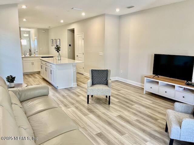 living area featuring recessed lighting, light wood-type flooring, and baseboards