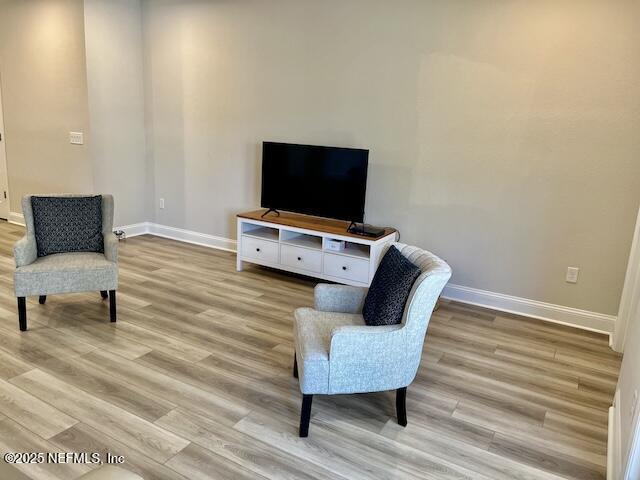 sitting room with baseboards and light wood-type flooring