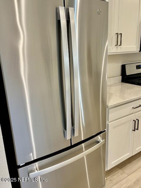 kitchen with stainless steel appliances, light wood finished floors, and white cabinetry