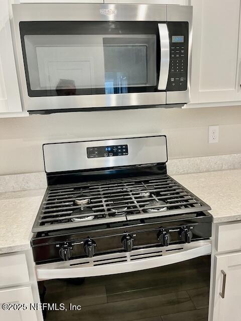 room details featuring white cabinets, stainless steel appliances, and light countertops