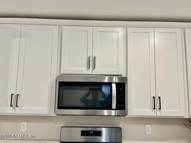 interior details featuring stainless steel microwave and white cabinetry