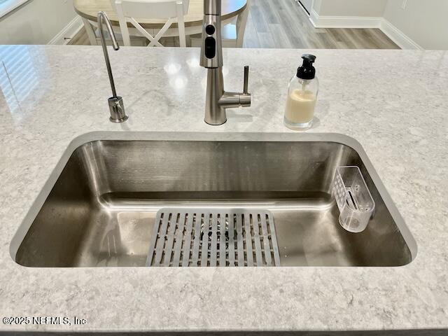 room details with wood finished floors, baseboards, and a sink