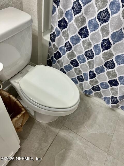 full bathroom with toilet and a shower with shower curtain