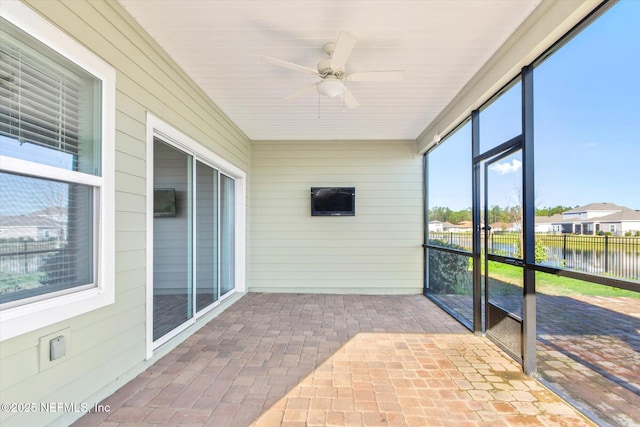 unfurnished sunroom with a ceiling fan and a water view