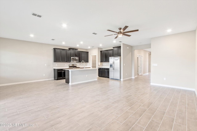 kitchen with dark cabinetry, visible vents, stainless steel appliances, light countertops, and open floor plan