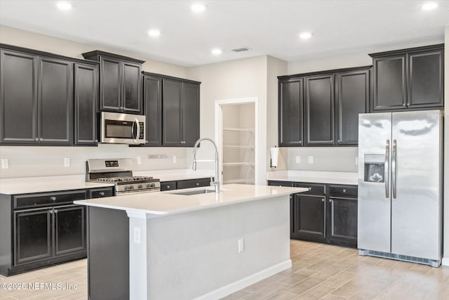 kitchen featuring visible vents, a sink, dark cabinetry, appliances with stainless steel finishes, and wood tiled floor