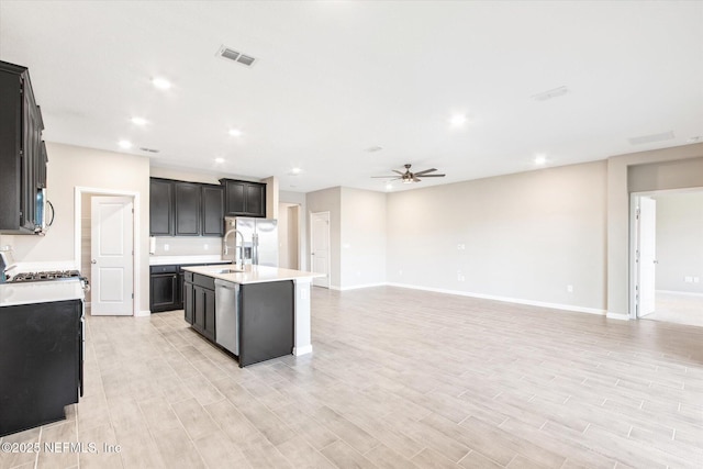 kitchen with a ceiling fan, visible vents, stainless steel appliances, light countertops, and open floor plan