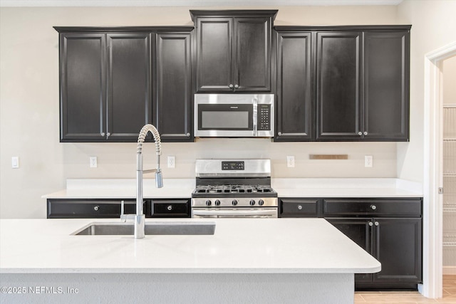 kitchen featuring a sink, light countertops, dark cabinets, and stainless steel appliances