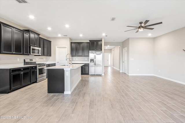 kitchen with a sink, open floor plan, stainless steel appliances, light countertops, and ceiling fan