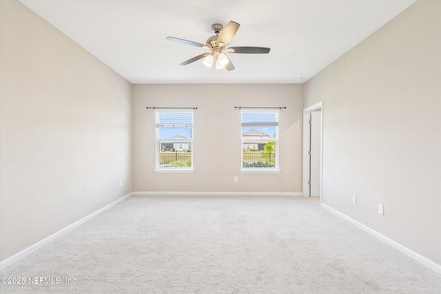 spare room featuring baseboards, light carpet, and ceiling fan