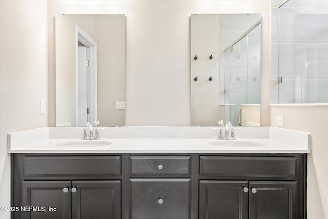 bathroom with double vanity, a stall shower, and a sink