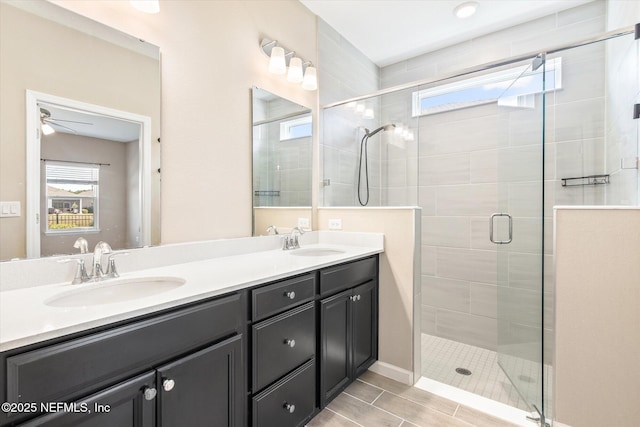 bathroom featuring ceiling fan, a shower stall, double vanity, and a sink