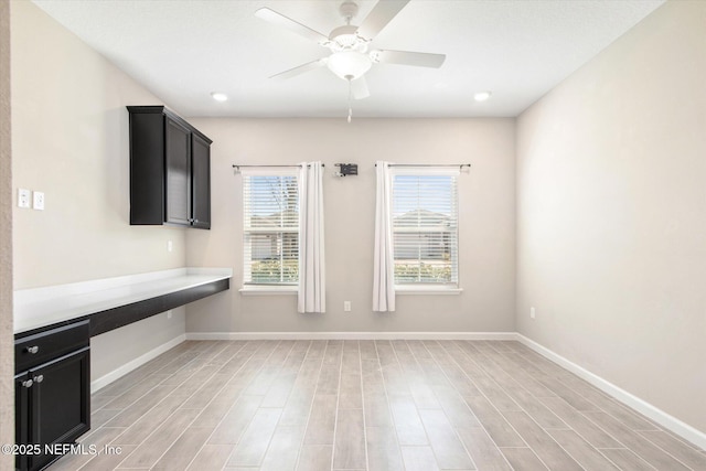 unfurnished office featuring a ceiling fan, light wood-style floors, and baseboards