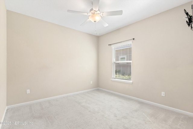 carpeted spare room featuring baseboards and ceiling fan